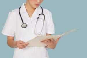 Picture Of Female Doctor Reading Liability Claims Medical Report